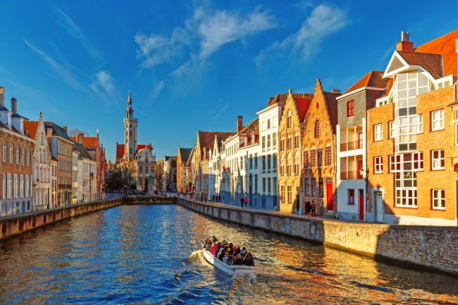 Tourist boat on canal Spiegelrei and Jan Van Eyck Square in the morning in Bruges, Belgium