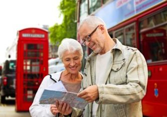 family, age, tourism, travel and people concept - senior couple with map over london city street background