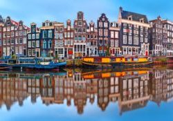 Panorama of Amsterdam canal Singel with typical dutch houses and houseboats during morning blue hour, Holland, Netherlands.