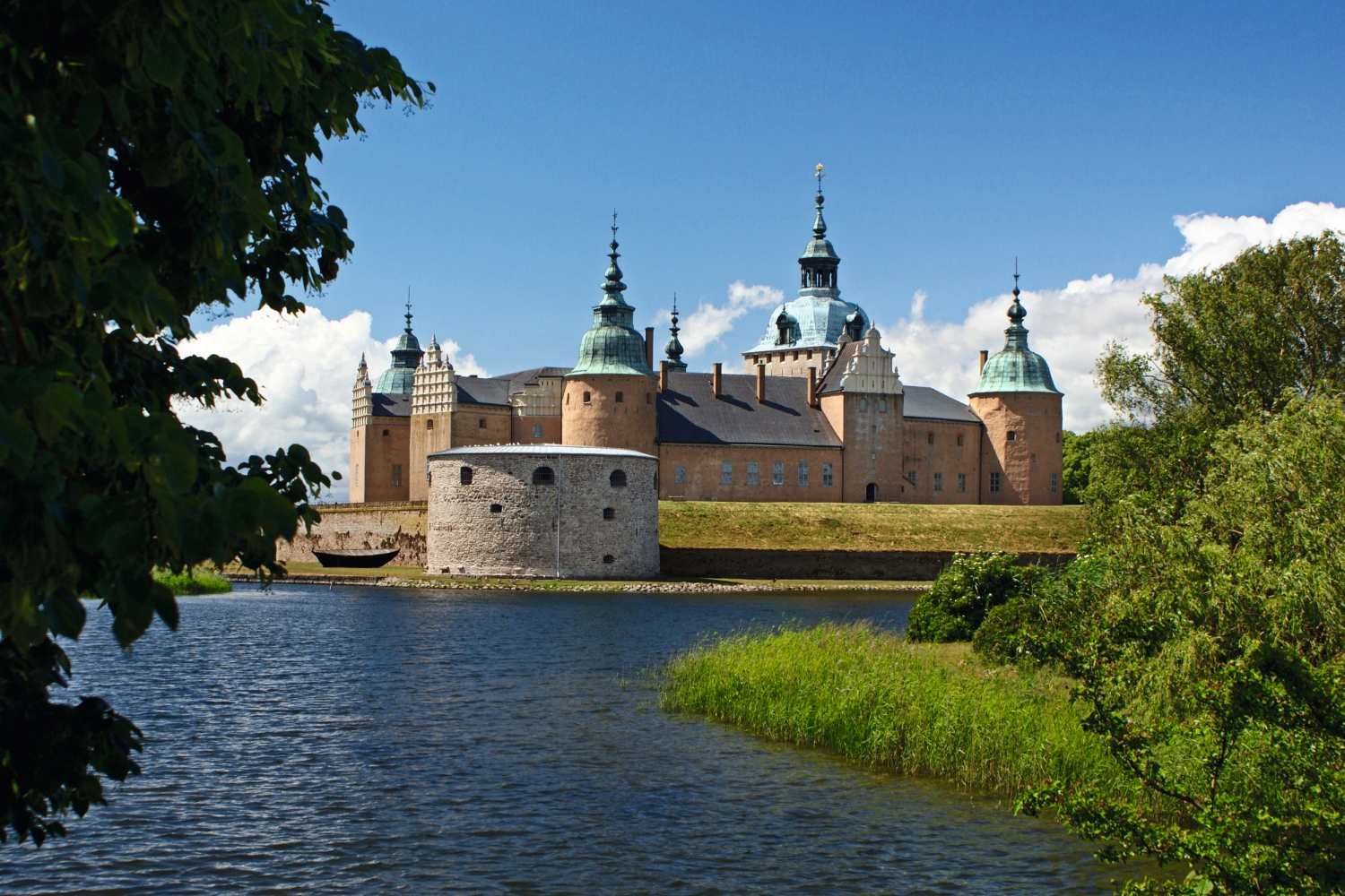 Historisches Schloss am Wasser mit Türmen und blauen Dächern.