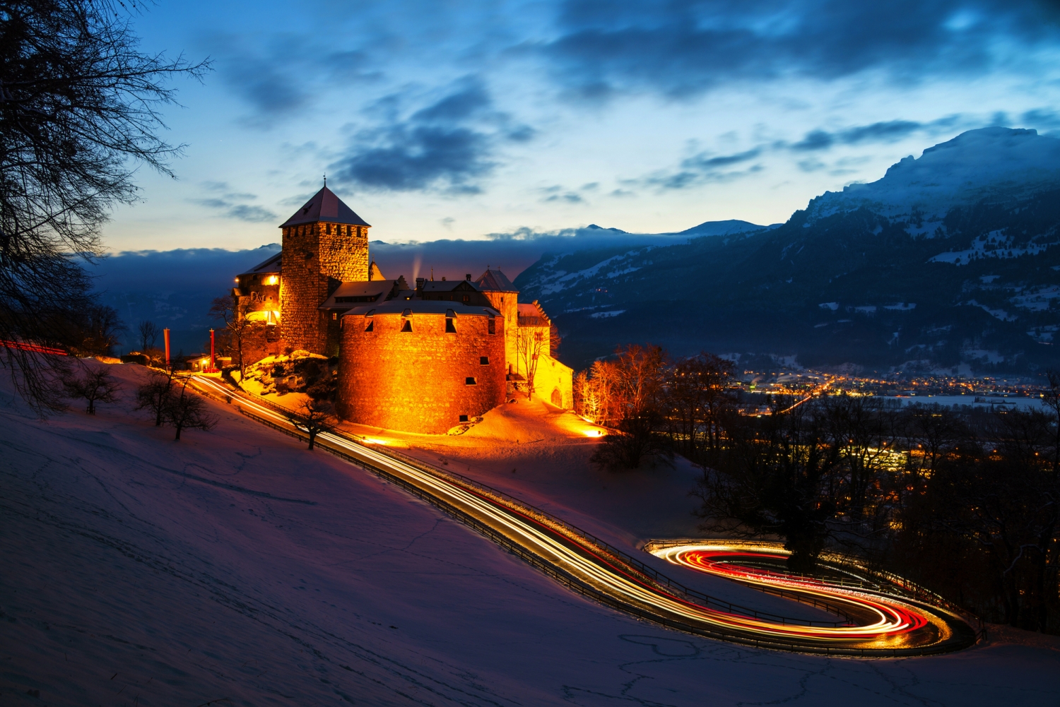 ©Madrugada Verde - stock.adobe.com Burg auf Hügel bei Dämmerung mit beleuchteten Wegen und verschneiter Landschaft.