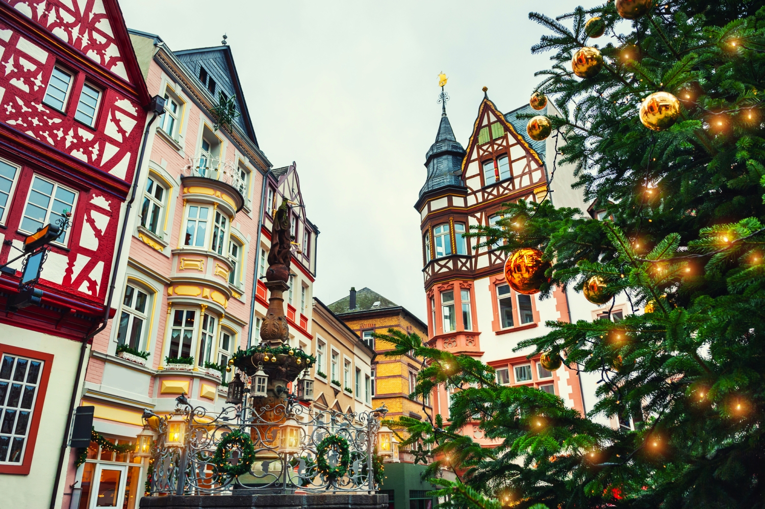 Fachwerkhäuser und geschmückter Weihnachtsbaum vor grauem Himmel.