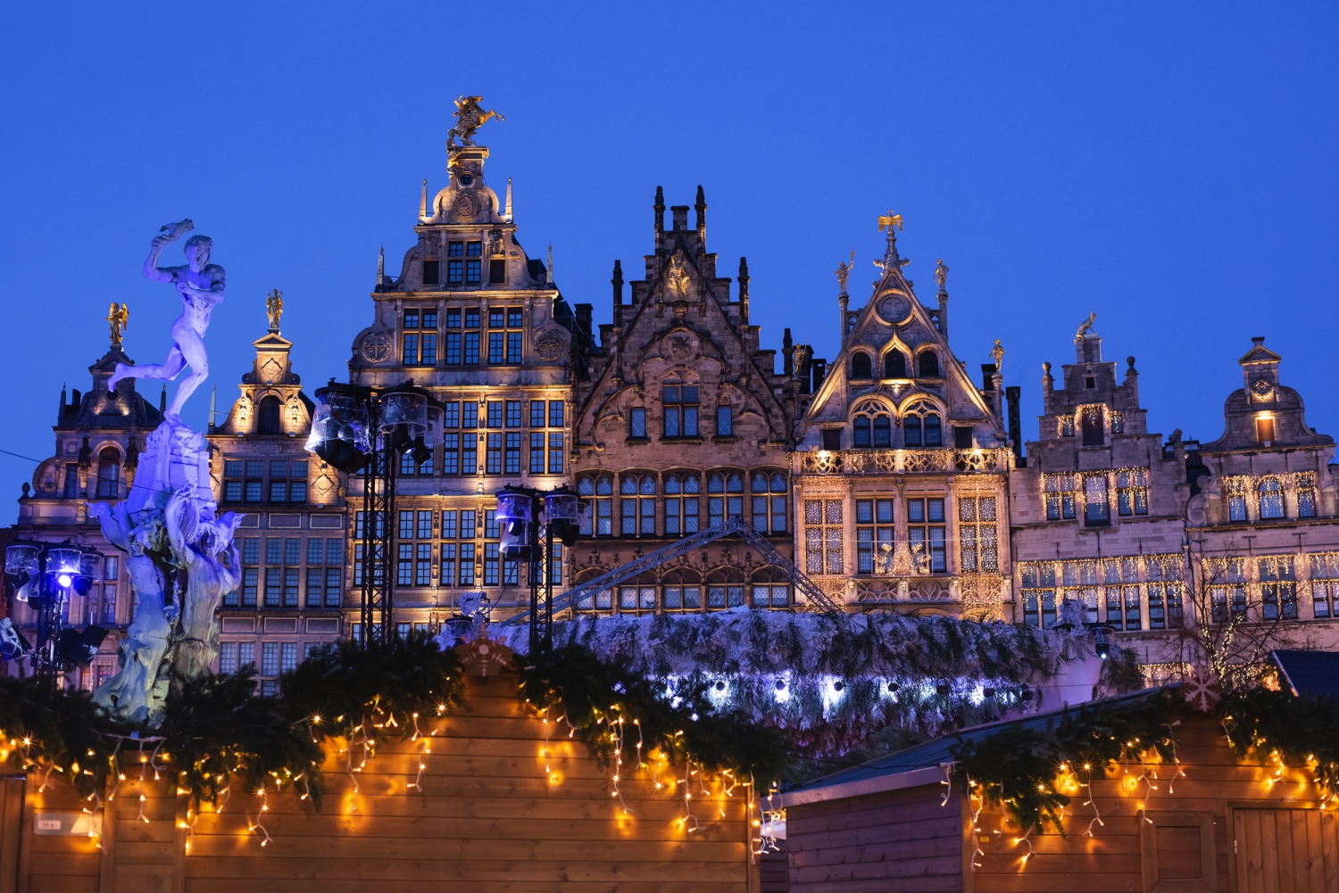 Historische Gebäude und Weihnachtsmarktlichter in Antwerpen bei Nacht.