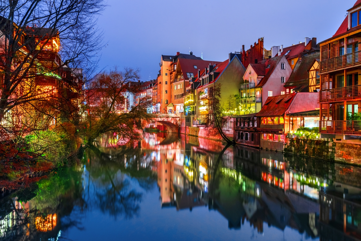 Malerische Stadtansicht mit Fachwerkhäusern am Fluss bei Dämmerung.