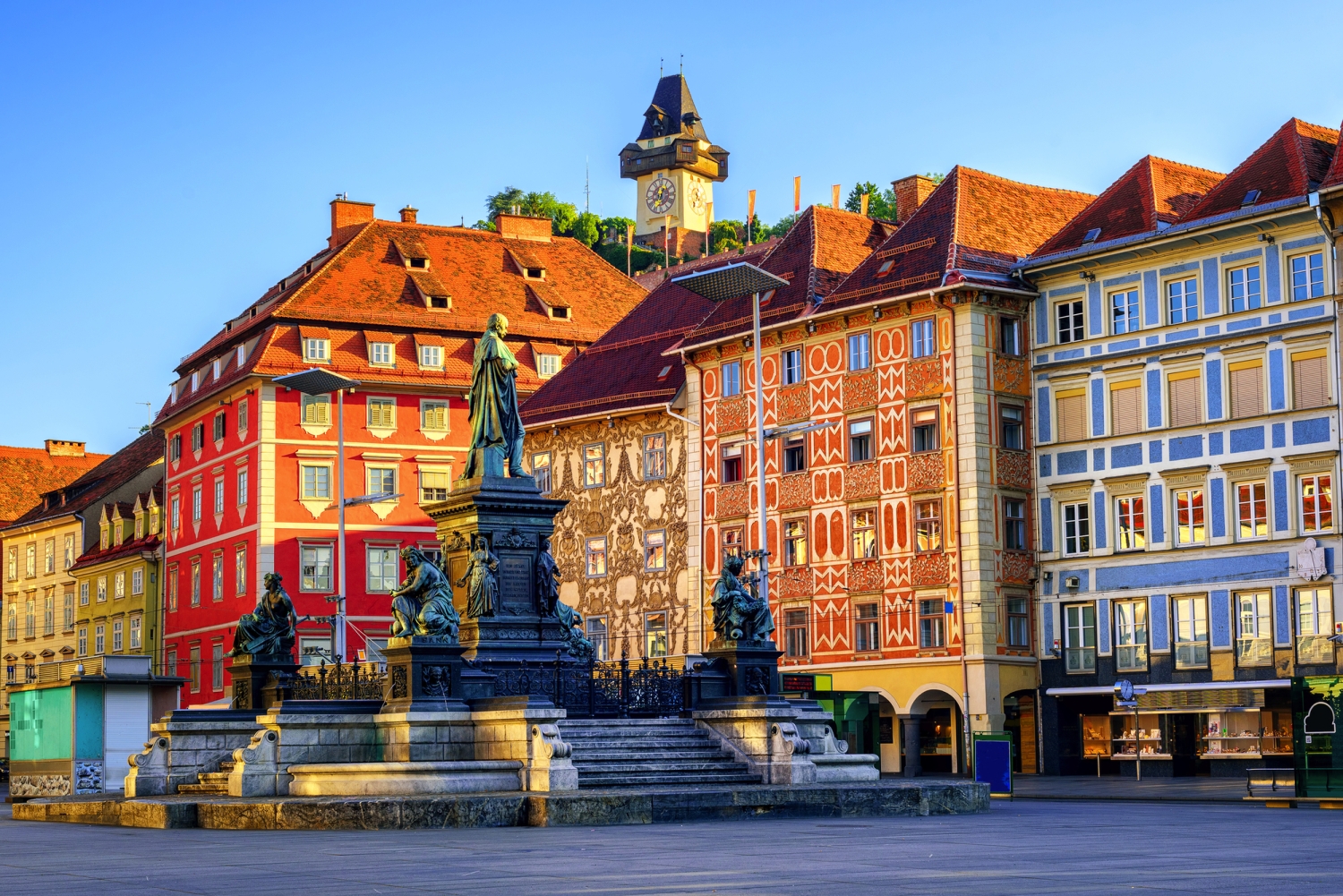 Hauptplatz in Graz mit Brunnen und umgebenden Gebäuden bei Tageslicht.