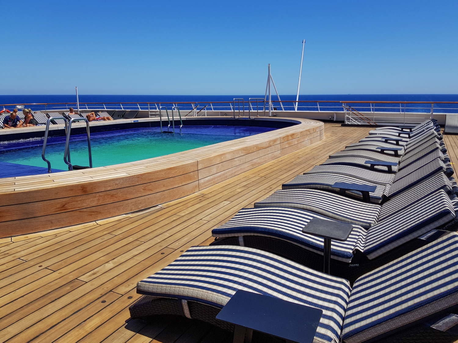 Pool auf dem Deck eines Schiffes mit Sonnenliegen und Meerblick