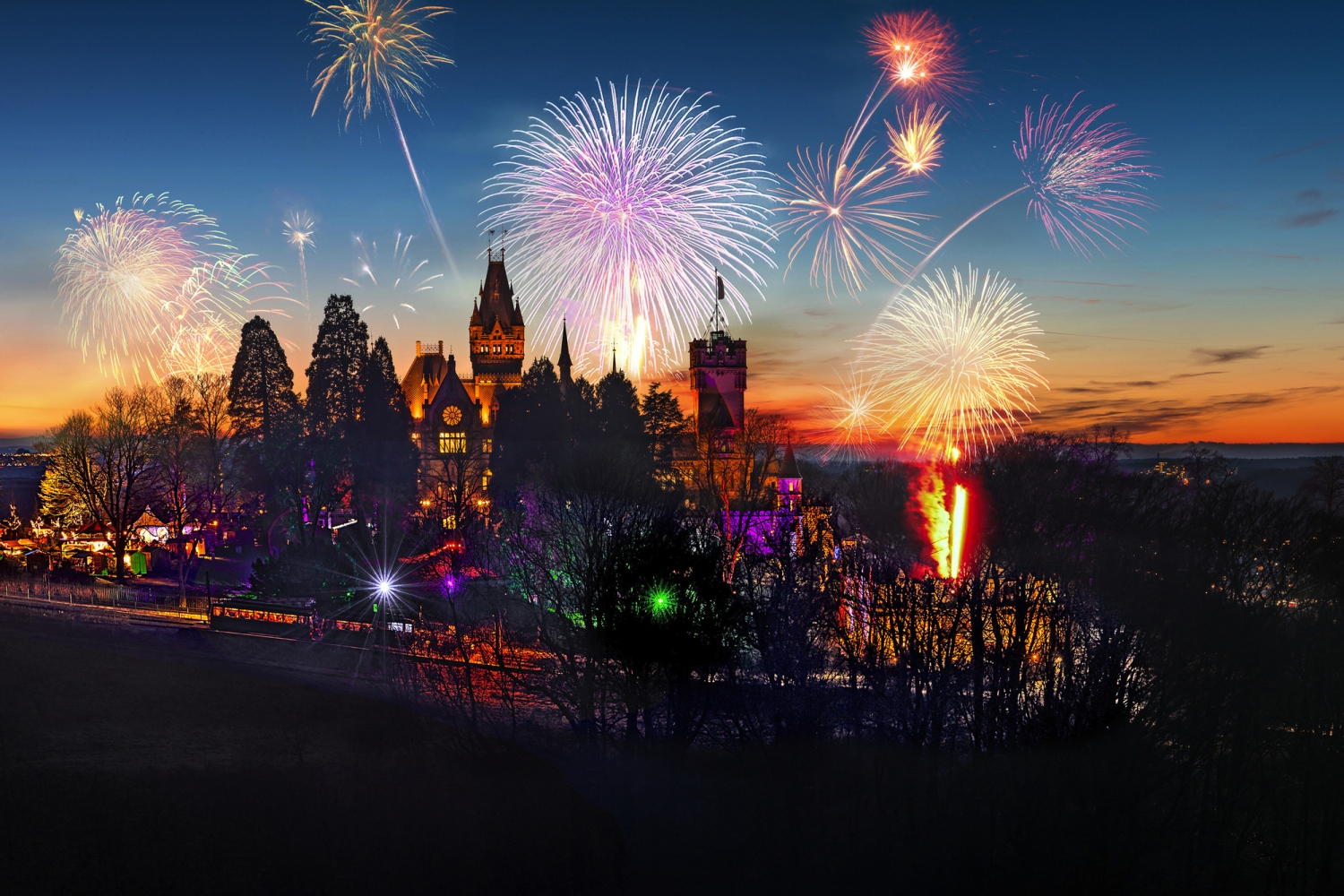 Feuerwerk über beleuchtetem Schloss bei Nacht