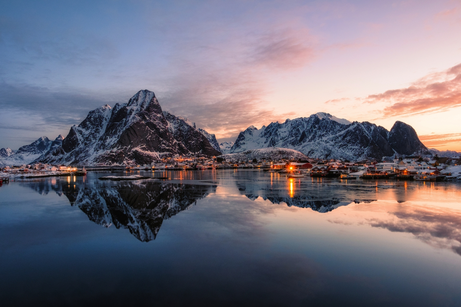 Fjordlandschaft bei Sonnenuntergang mit schneebedeckten Bergen und Wasserreflexionen