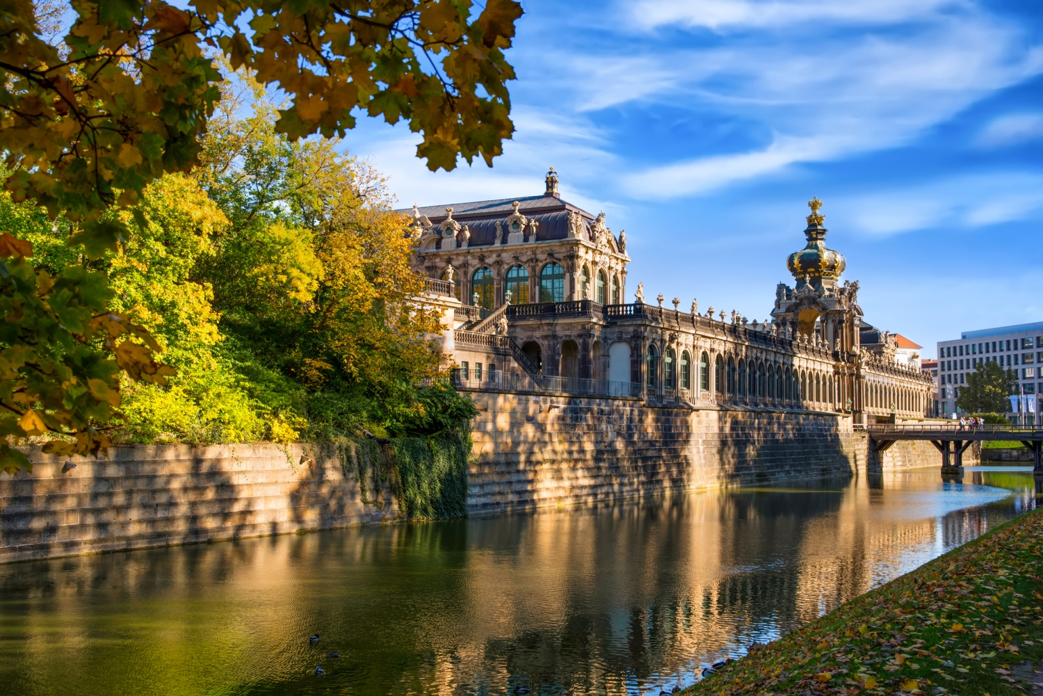 Barocker Gebäudekomplex am Wasser an einem sonnigen Tag mit blauem Himmel.