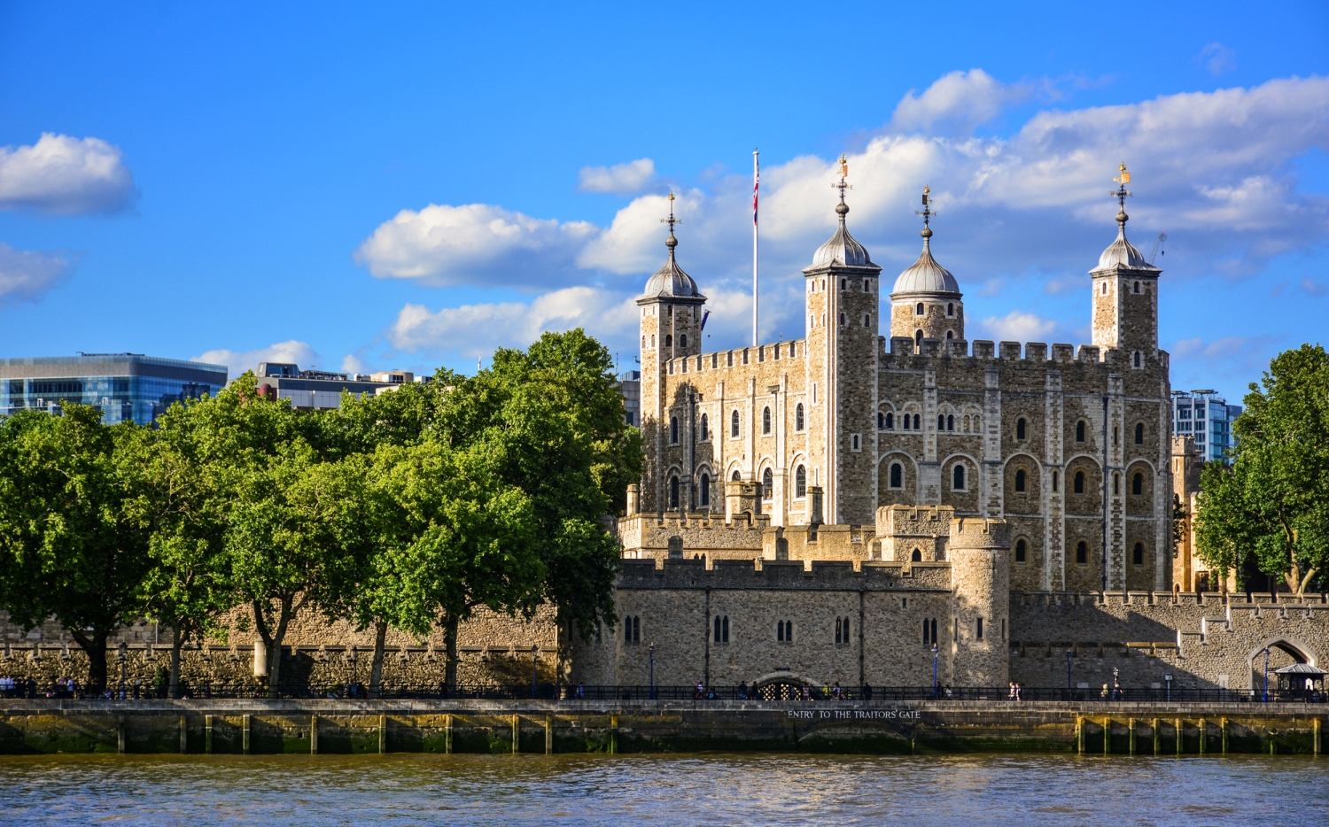 Tower of London am Ufer der Themse bei blauem Himmel und Wolken.