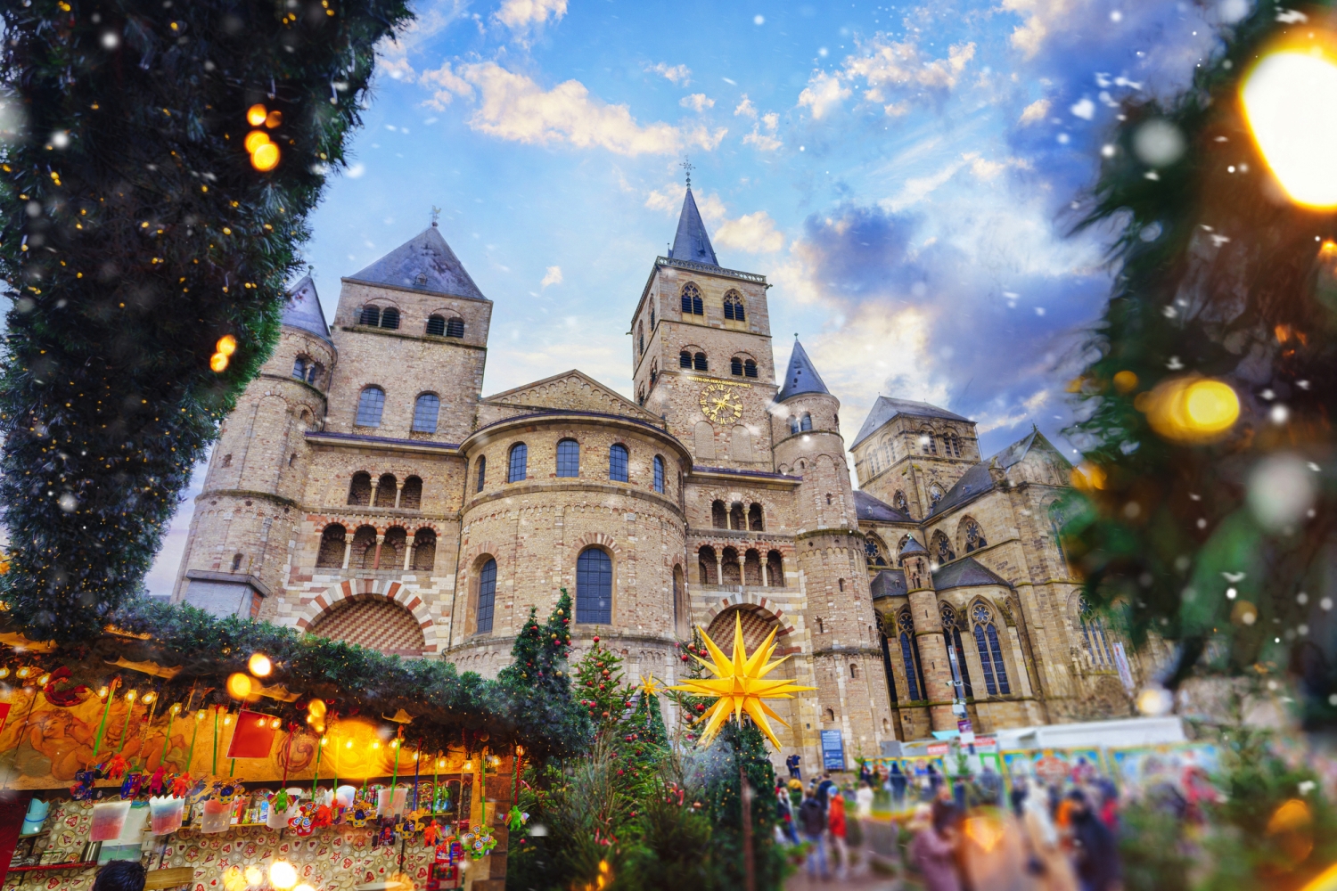 Weihnachtsmarkt vor historischer Kathedrale, beleuchtet und festlich geschmückt.