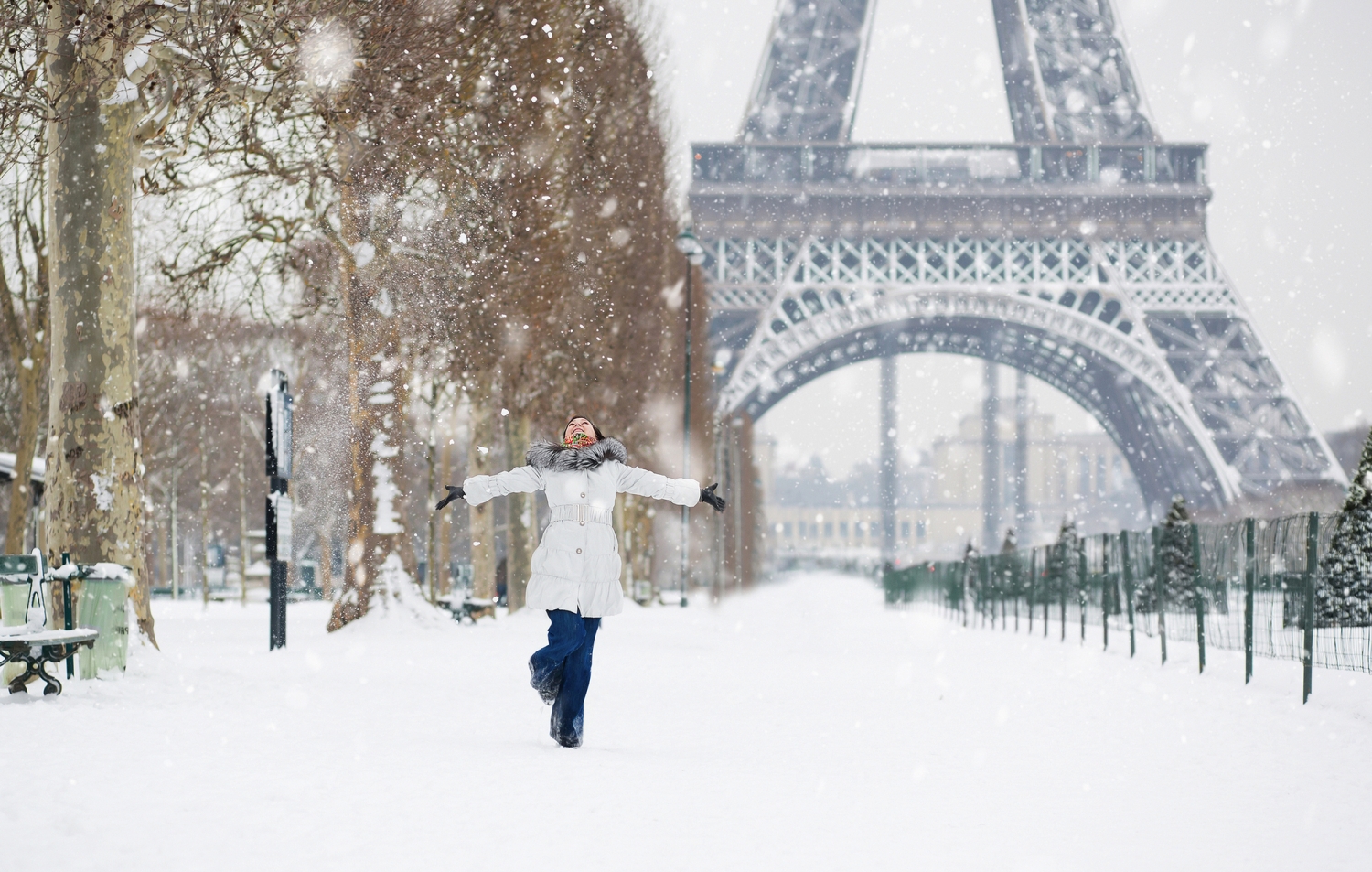 © Ekaterina Pokrovsky - stock.adobe.com Eine Person steht mit ausgebreiteten Armen im Schnee vor dem Eiffelturm in Paris im Winter.