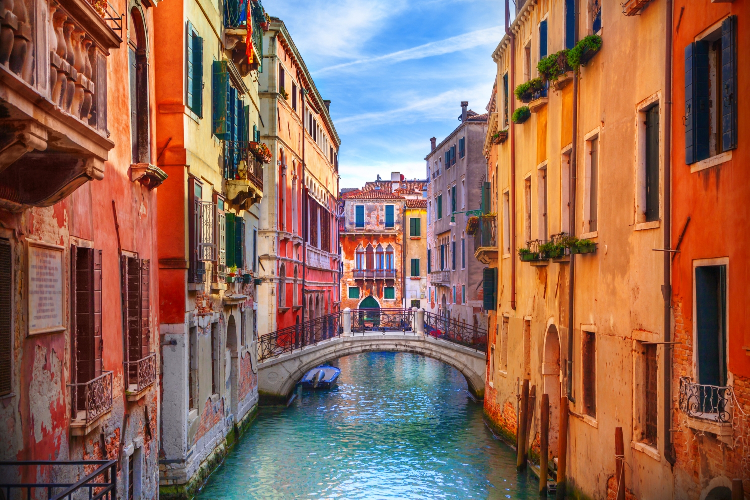 Kanal in Venedig mit bunten Häusern und einer kleinen Brücke über dem Wasser.