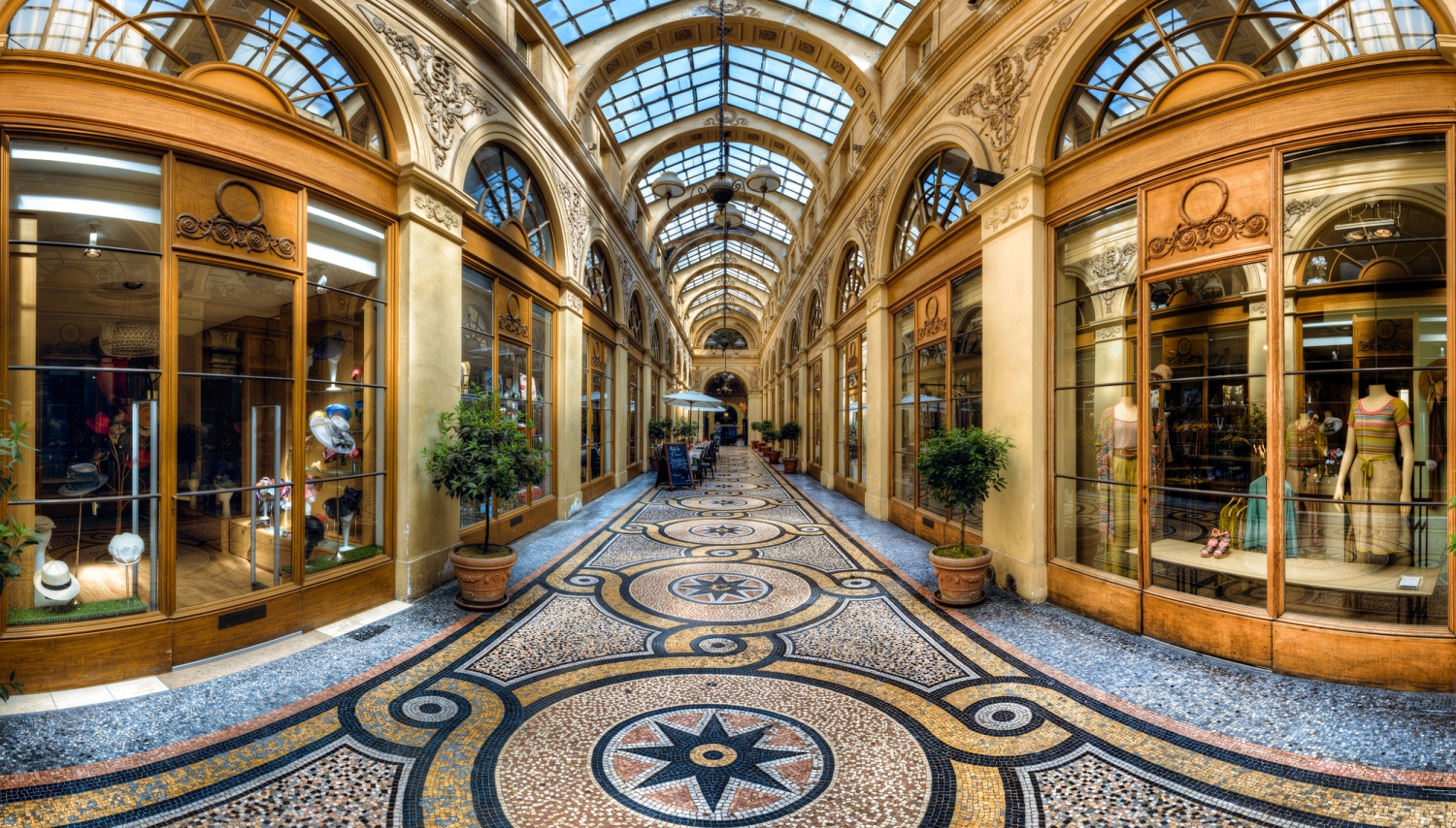 Arkadenpassage mit Glasdach, stilvollen Geschäften und verzierten Bodenfliesen.