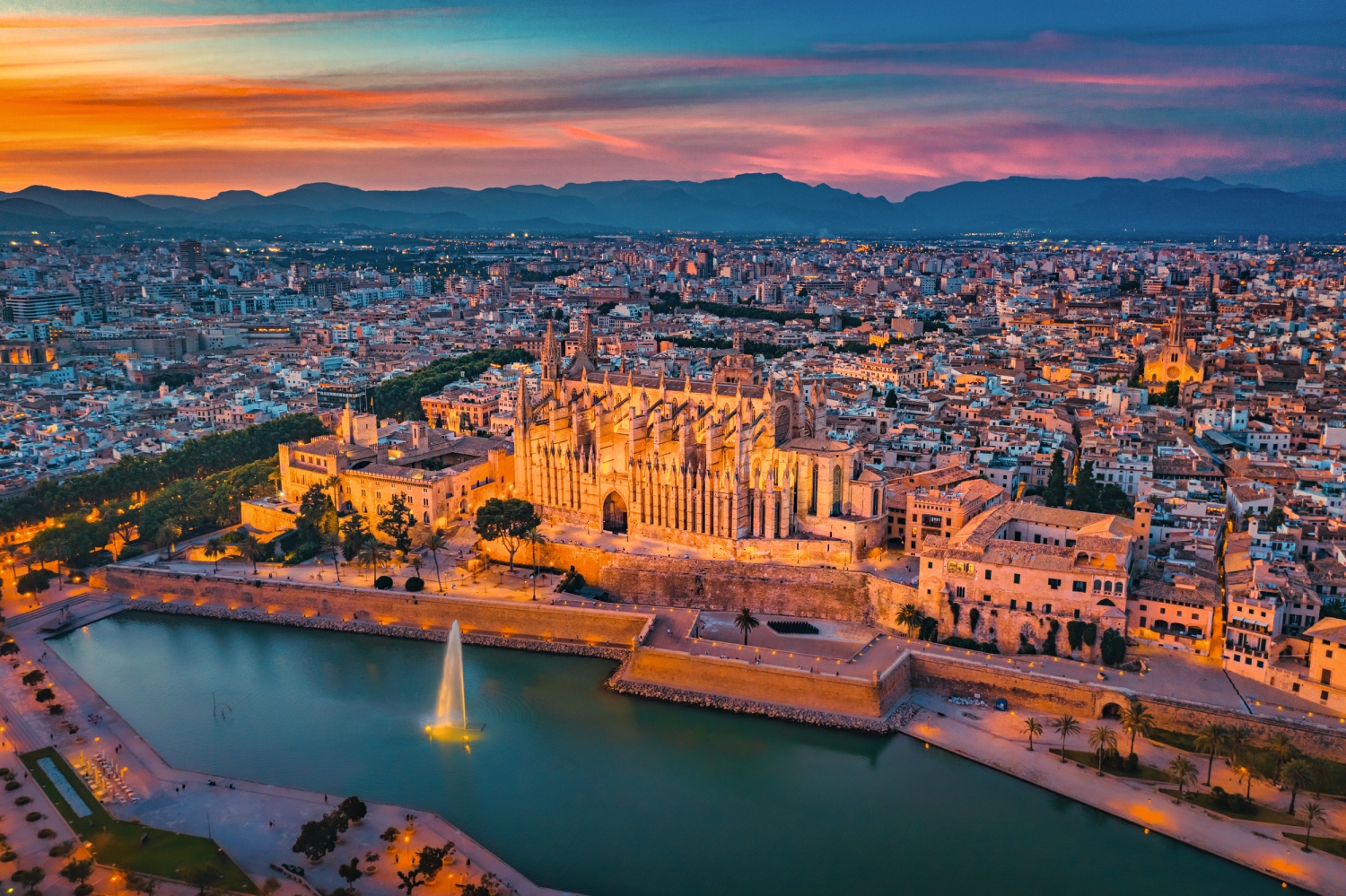 Luftaufnahme der Kathedrale von Palma bei Sonnenuntergang, Mallorca, mit Stadt und Wasser.