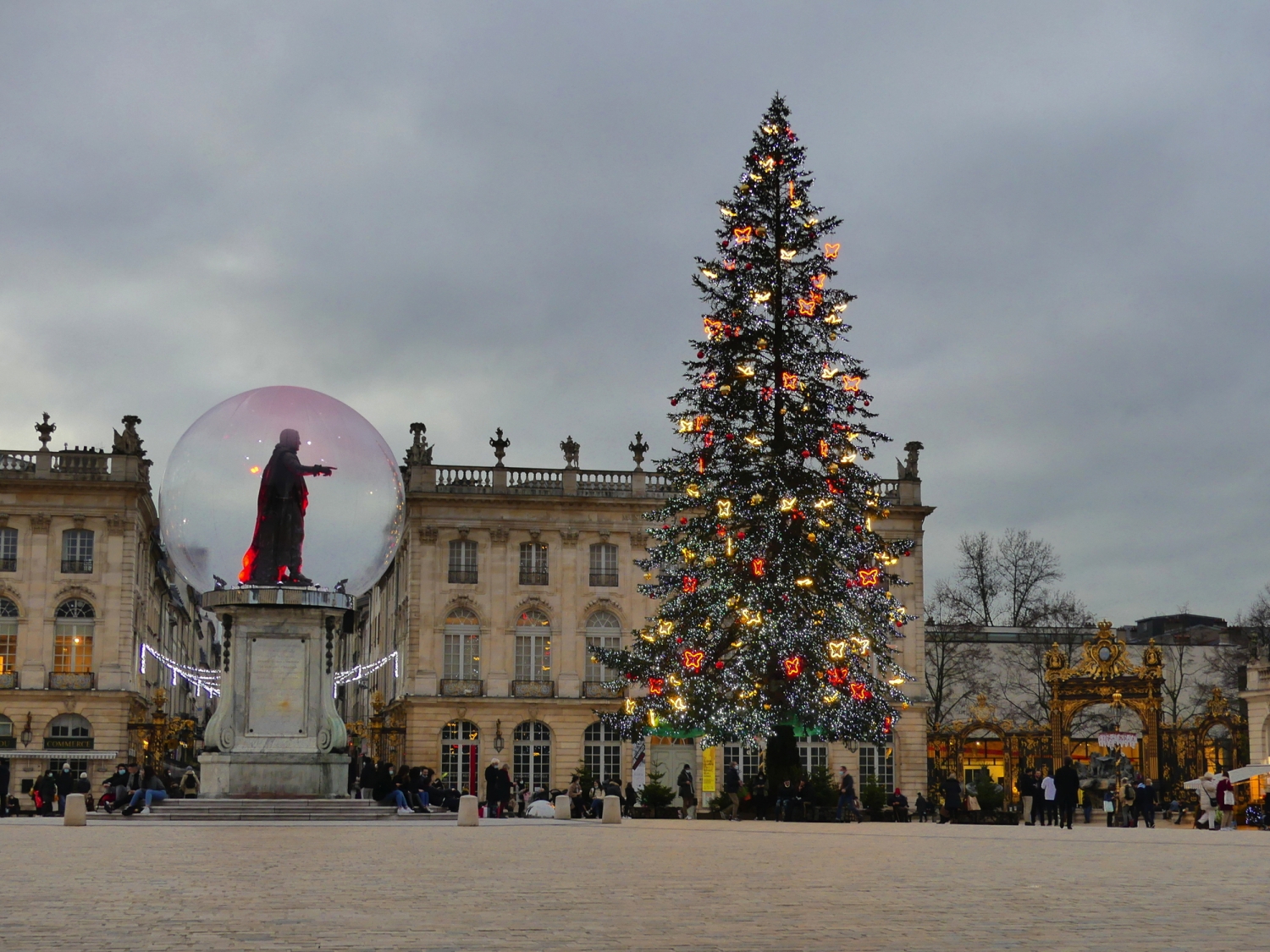 Weihnachtsbaum und Statue auf Platz vor historischem Gebäude