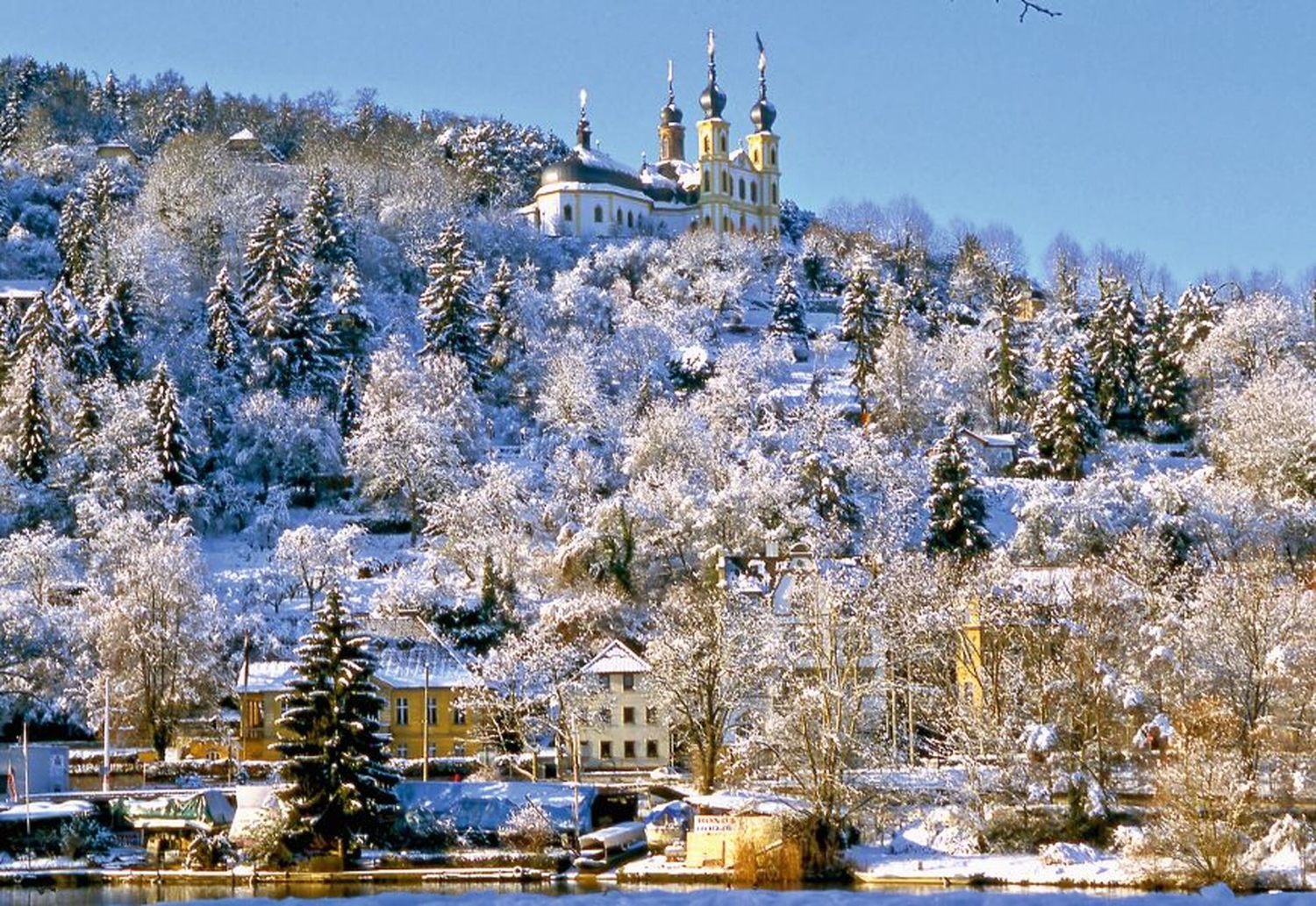 Eine verschneite Landschaft mit Kirche auf einem Hügel.