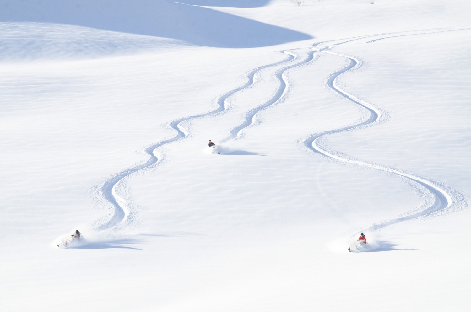 Drei Skifahrer ziehen Spuren im frischen Schnee.