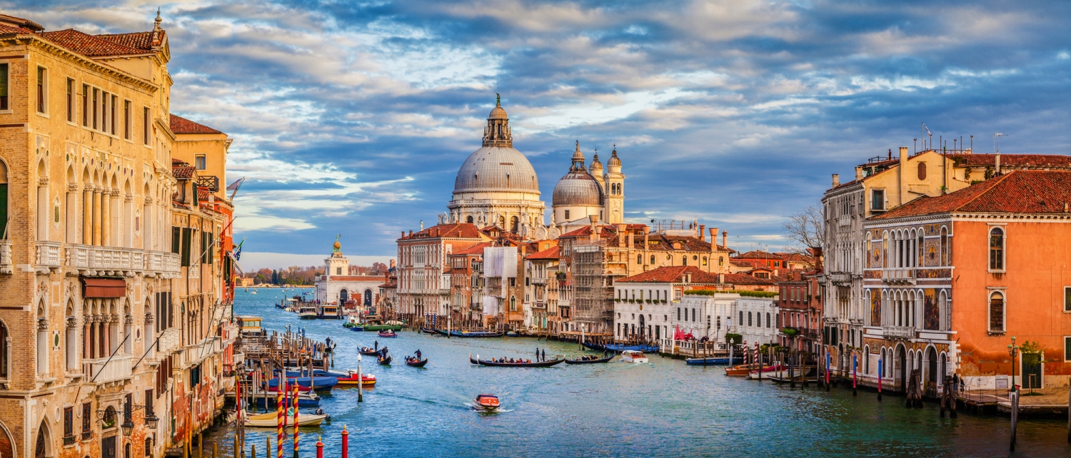 Blick auf den Canal Grande in Venedig mit Gondeln und historischen Gebäuden im Sonnenuntergang.