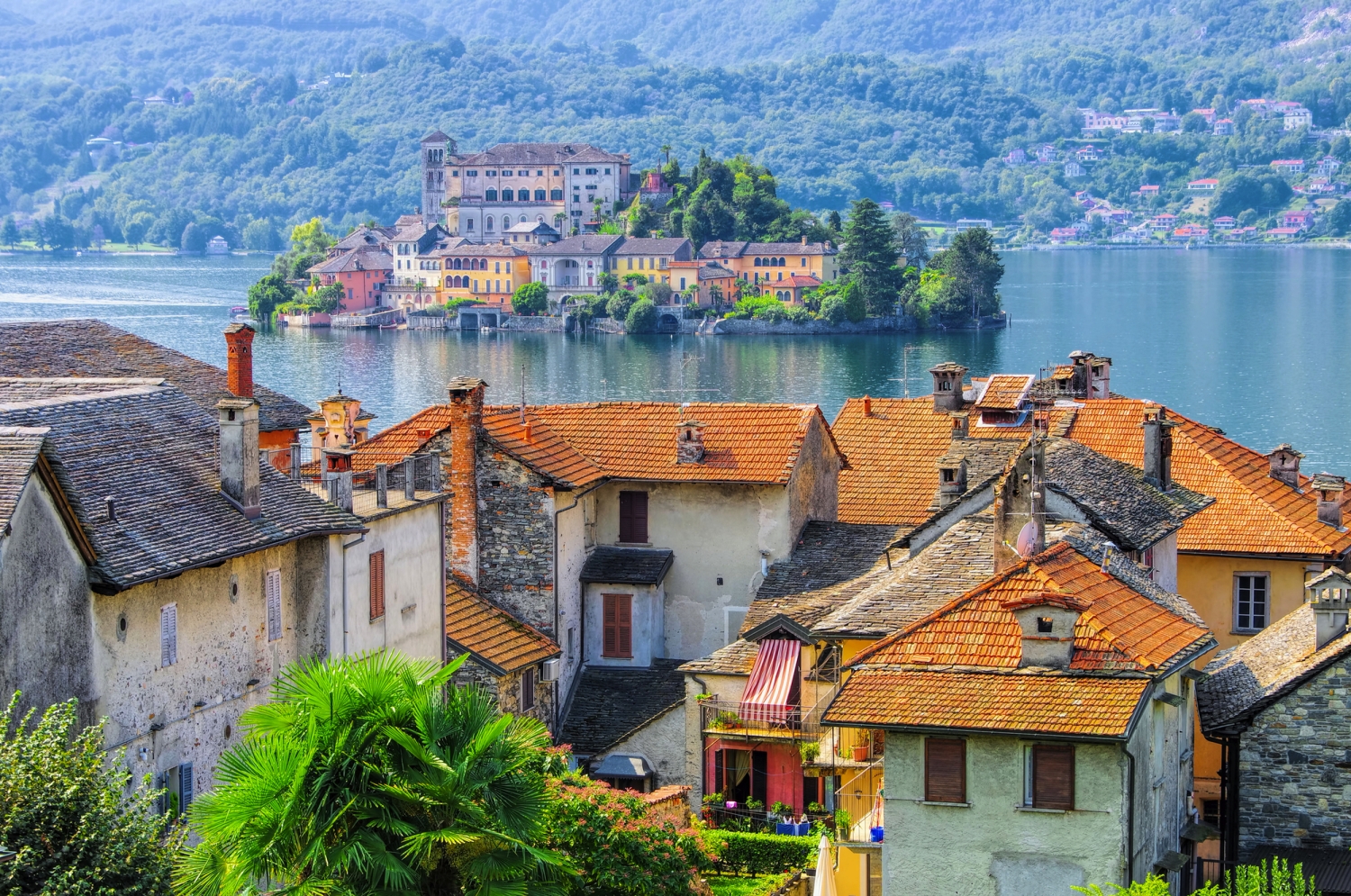 Blick auf Ortschaft mit bunten Dächern und See im Hintergrund