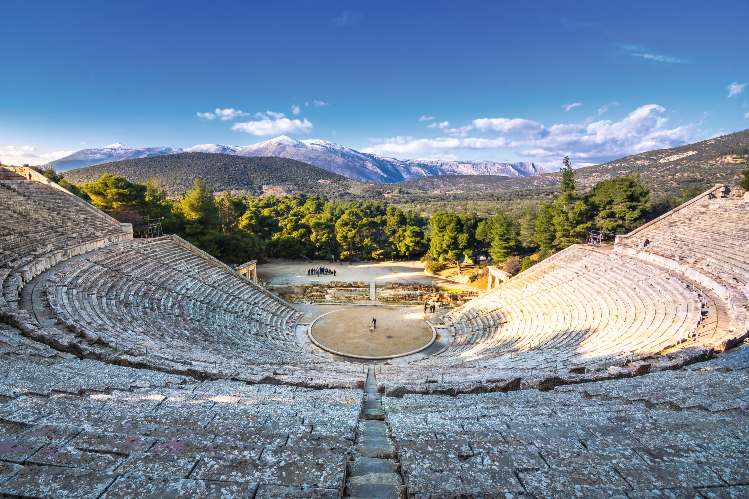 Antikes Amphitheater mit bewaldeter Berglandschaft im Hintergrund