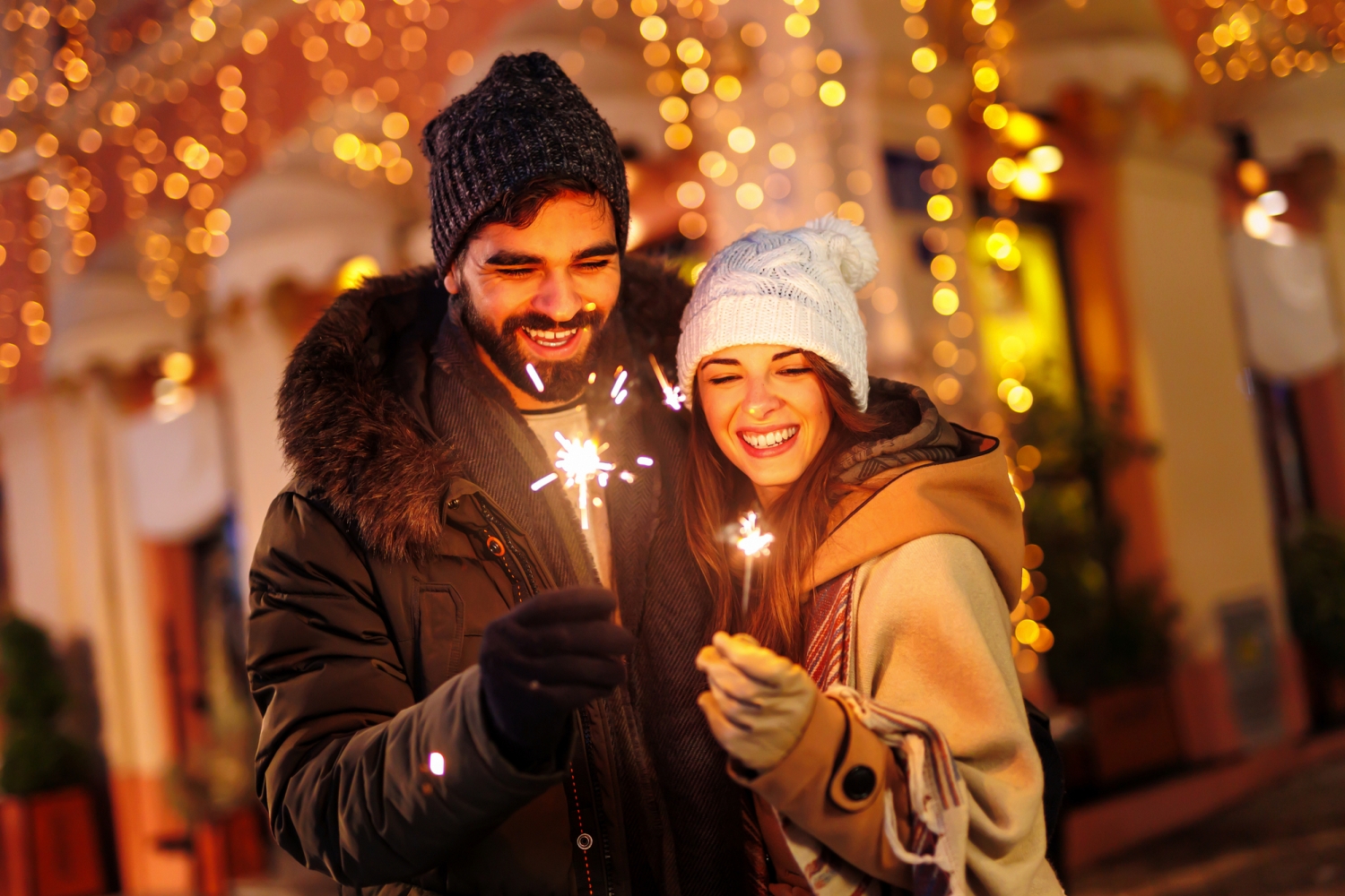 Paar hält Wunderkerzen auf einem festlichen Weihnachtsmarkt.
