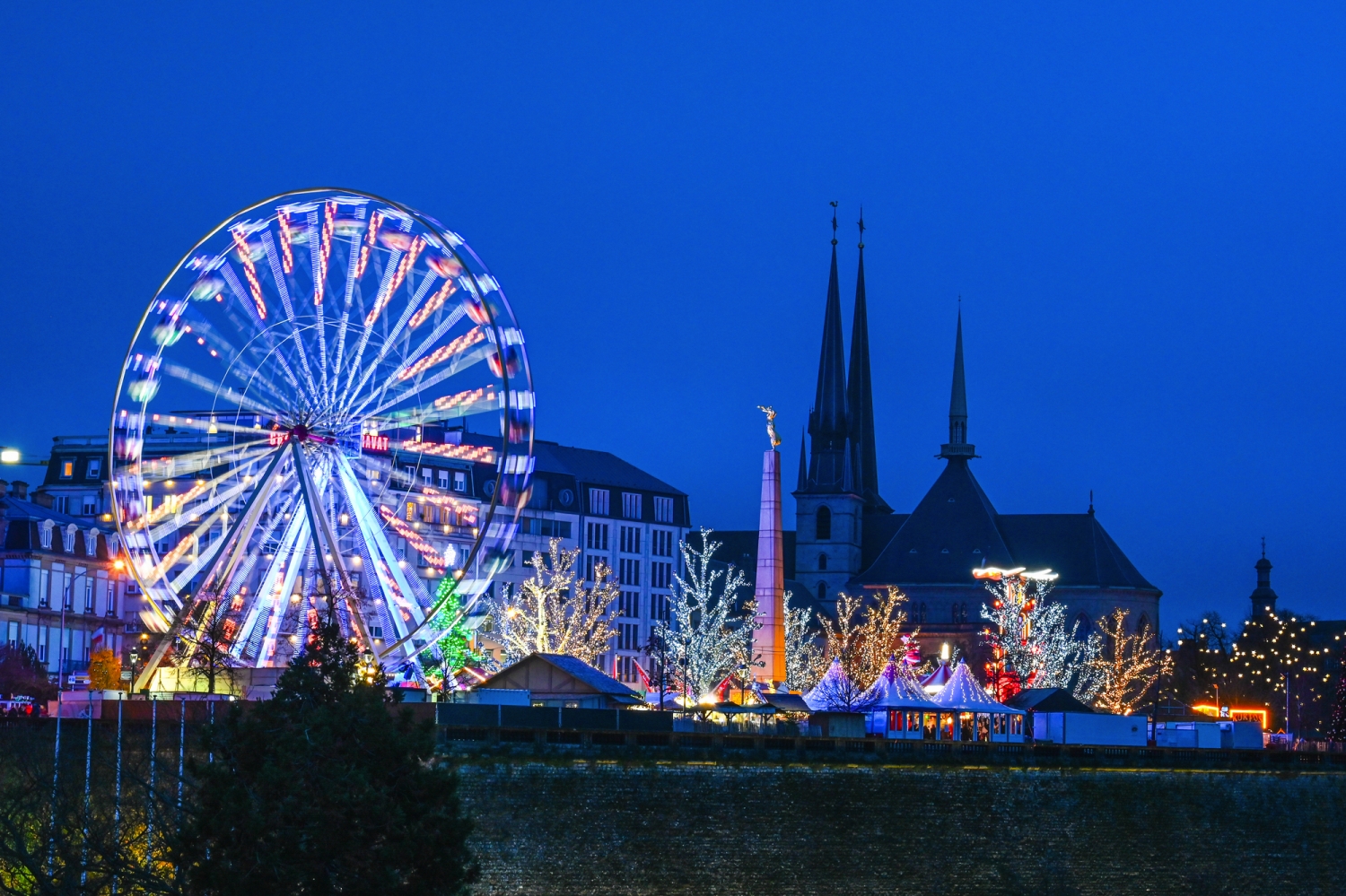 Riesenrad und beleuchtete Gebäude bei Nacht in einer Stadt.
