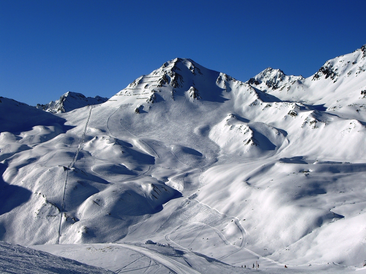Schneebedeckte Berglandschaft unter klarem blauen Himmel.