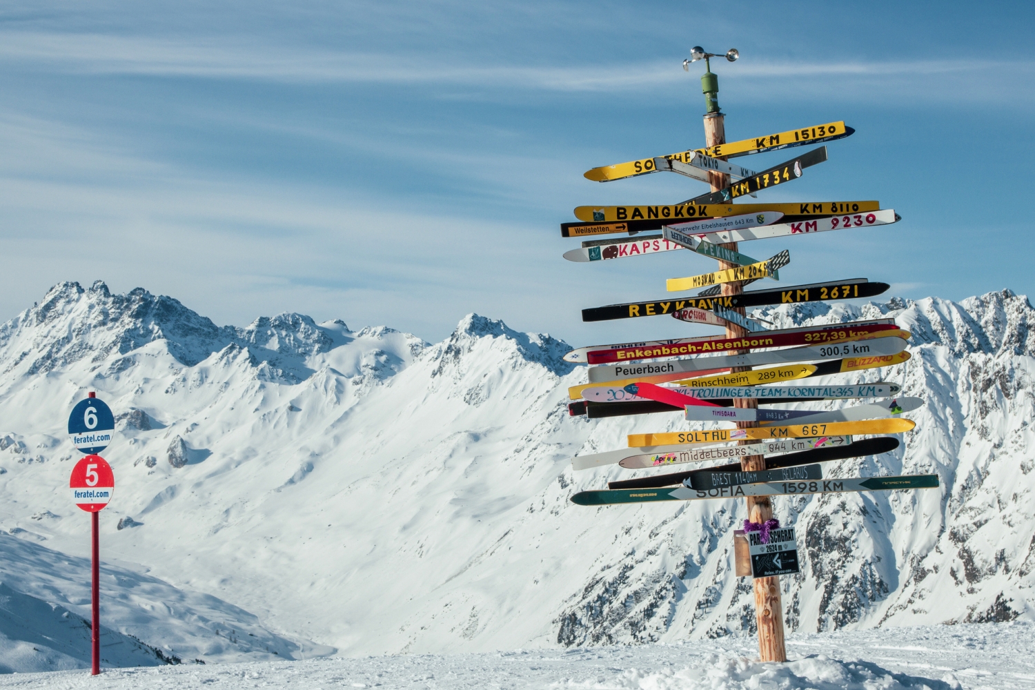 Wegweiser im Schnee vor verschneiten Bergen im Winter.