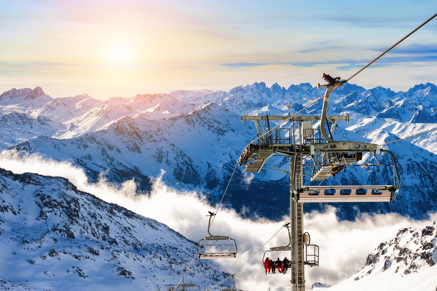 Skilift in einer verschneiten Berglandschaft bei Sonnenuntergang.