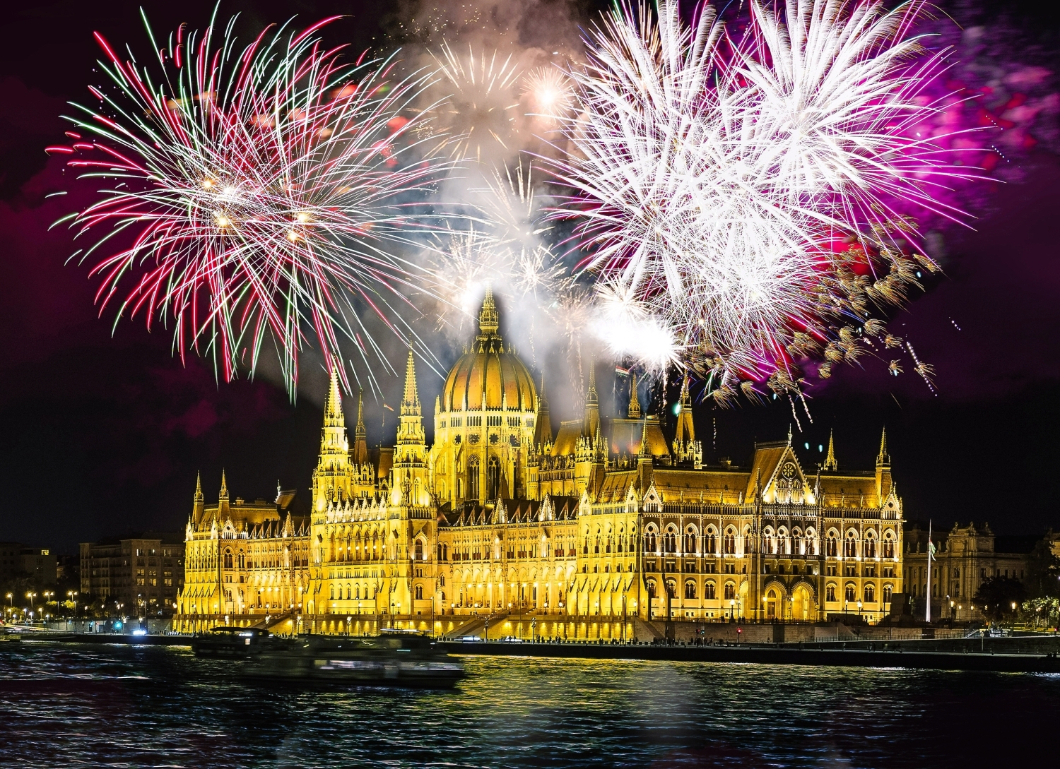 Feuerwerk über dem beleuchteten Parlamentsgebäude in Budapest bei Nacht.