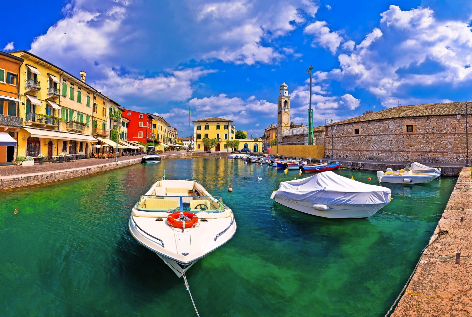 Bunte Häuser und Boote im Hafen einer historischen italienischen Stadt.