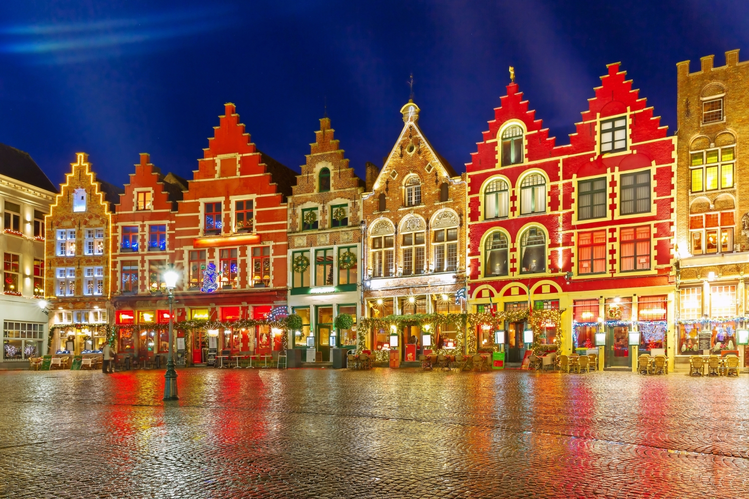 Beleuchtete historische Gebäude am Marktplatz in Brügge bei Nacht.